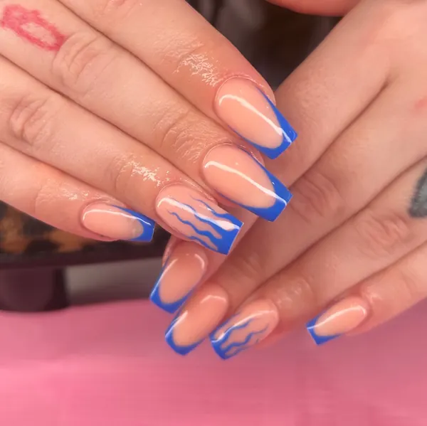 Long square nude nails with cobalt blue French tips and blue wavy line art